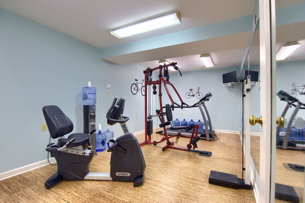 A small home gym with various exercise equipment including a treadmill, stationary bike, and weights.