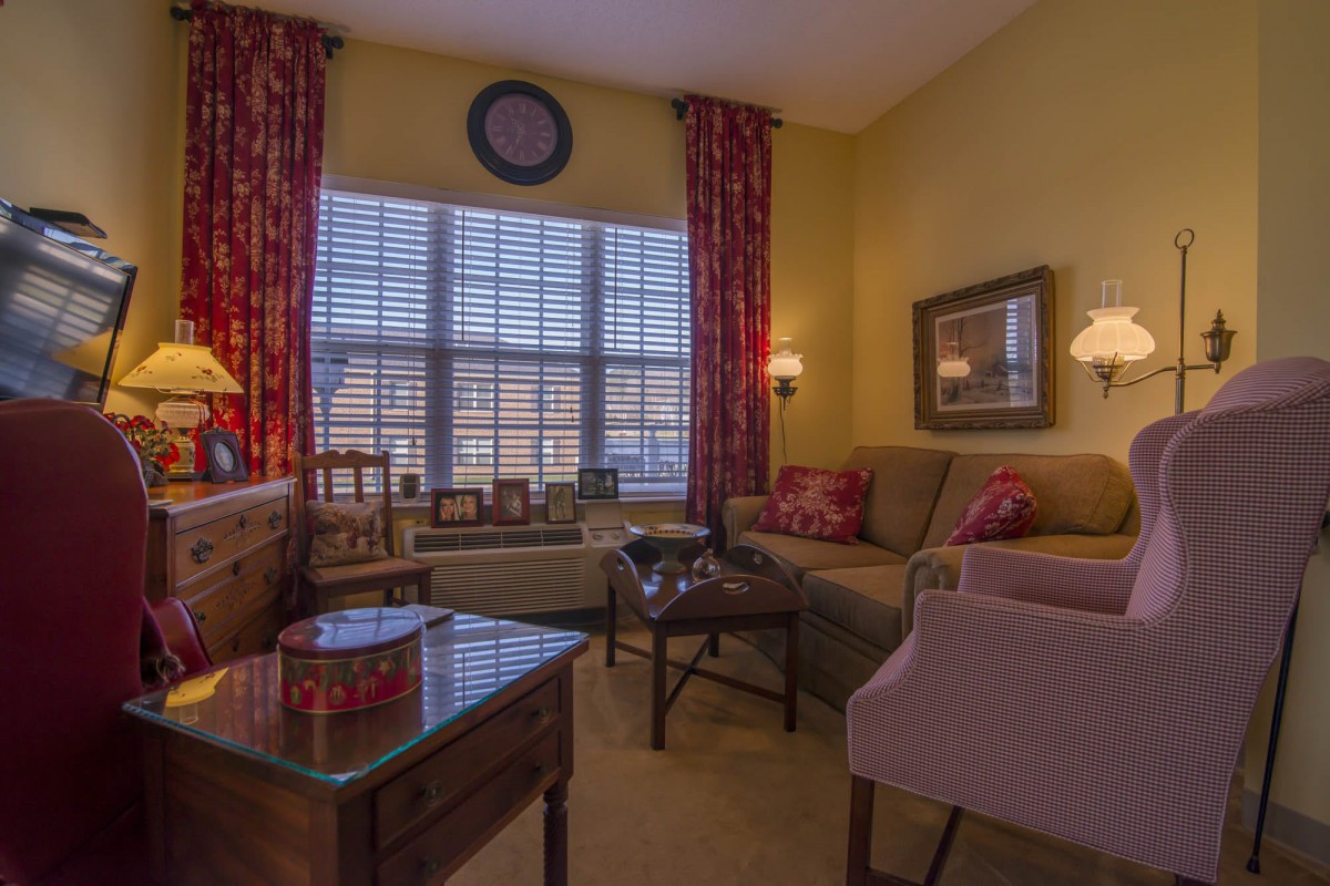 A cozy living room with warm lighting, featuring a sofa, armchairs, and decorative elements.