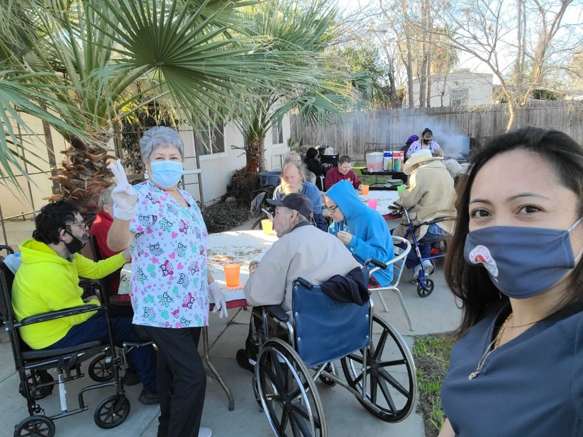 A group of people enjoying an outdoor gathering, with attendees in wheelchairs and wearing masks.