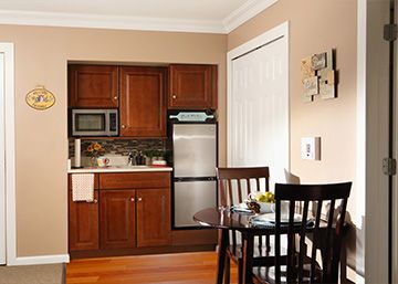 A cozy kitchen with wooden cabinets, featuring a mini fridge, microwave, and a small dining area.