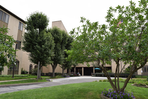 A view of a building surrounded by trees and a manicured lawn.