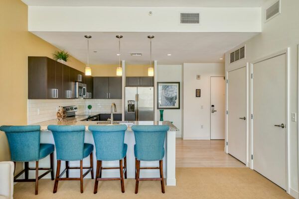 A modern kitchen with teal bar stools and pendant lighting.