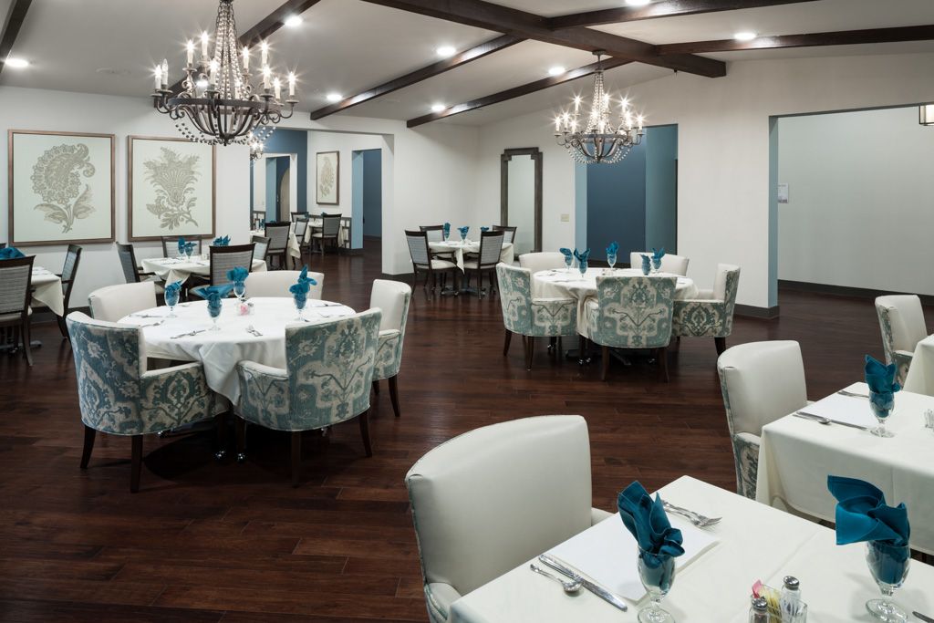 A well-decorated dining room with elegant chandeliers and neatly arranged tables and chairs.