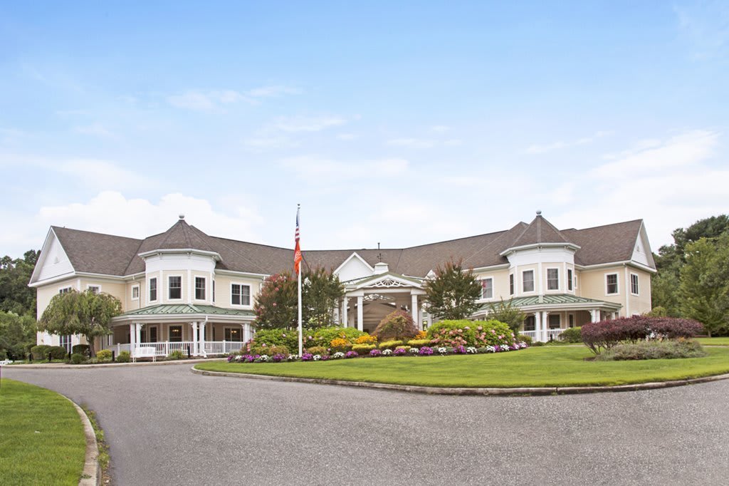 A grand building with landscaped gardens and a flagpole at the entrance.