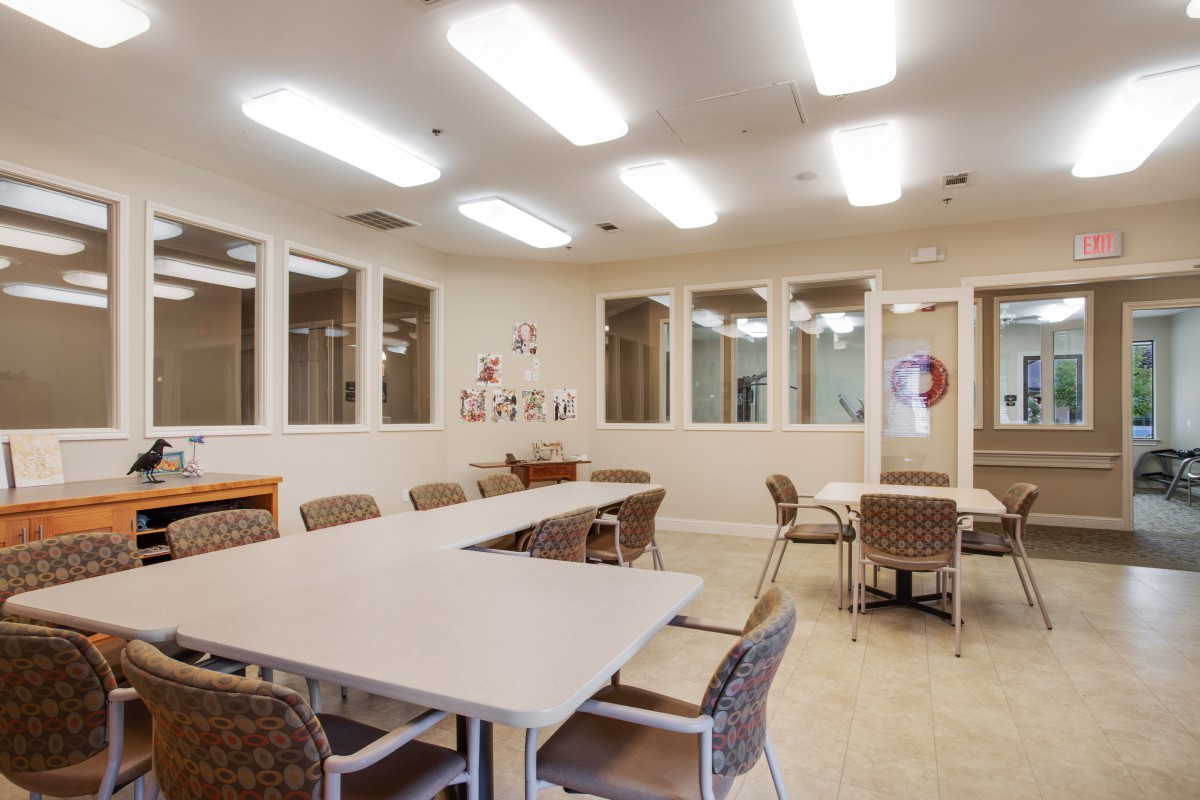A well-lit meeting room with tables and chairs arranged for a group discussion.