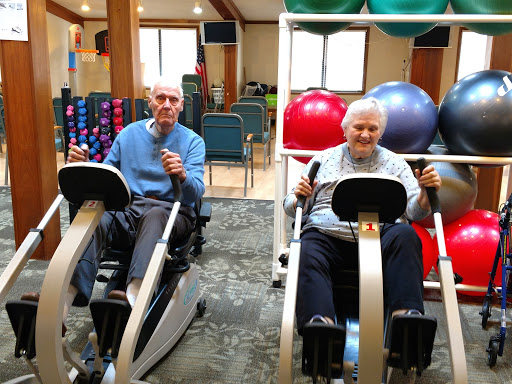 Seniors engaging in fitness activities together at a gym.