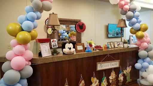 A vibrant reception area decorated with balloons and a Mickey Mouse plush toy, creating a cheerful atmosphere.