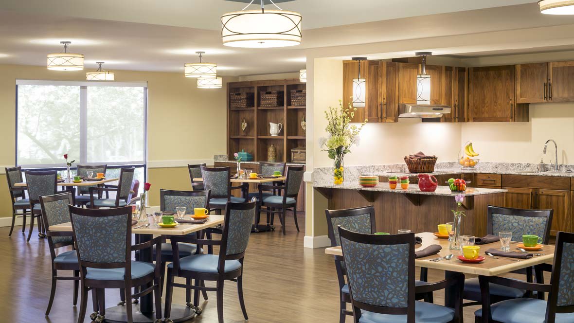 A modern dining room with neatly arranged tables and chairs, featuring stylish lighting and decor.