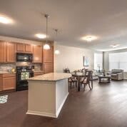 A modern open floor plan featuring a kitchen with wooden cabinets and a living area.