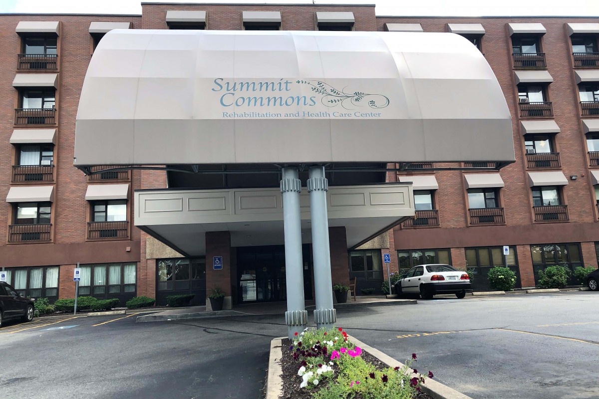 The front entrance of a building with an awning and landscaping.