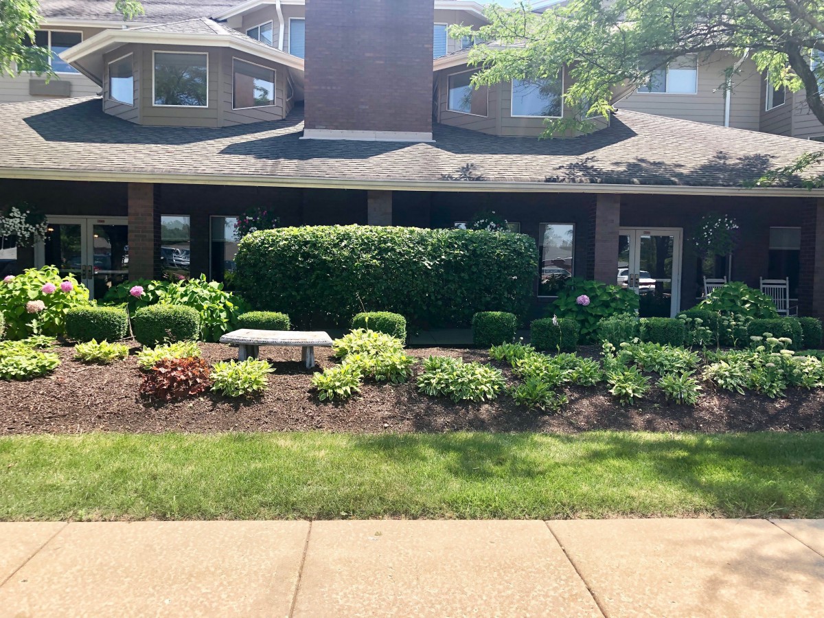 A well-maintained building with lush landscaping under bright sunlight.