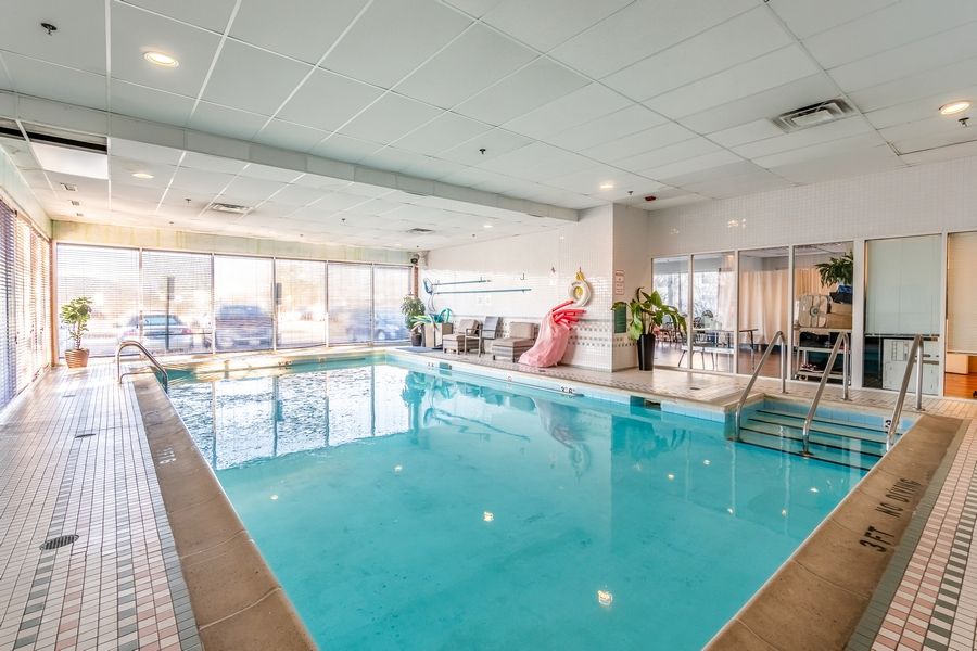 An indoor swimming pool with a large pink water slide and natural lighting.