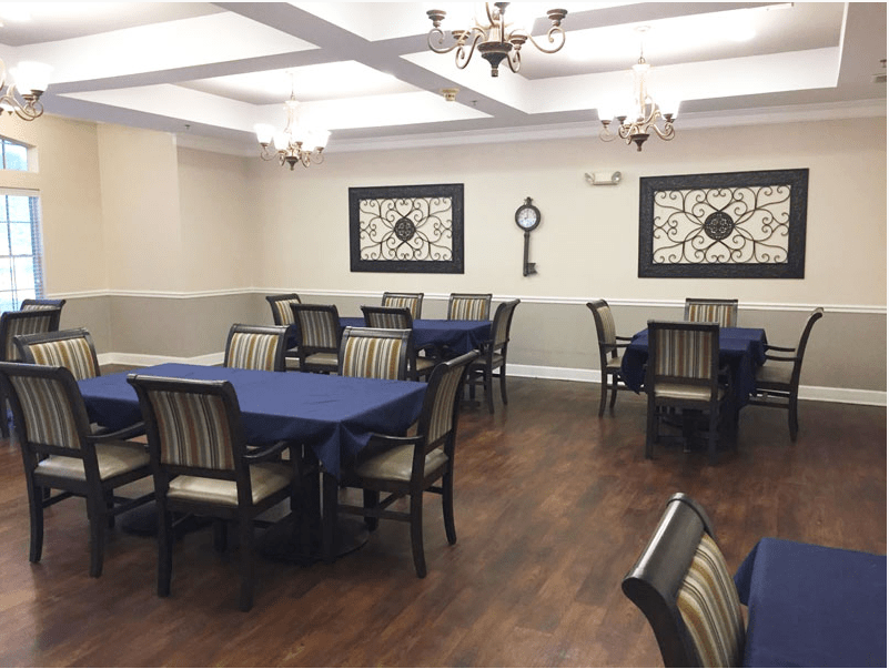 A well-decorated dining room with blue tablecloths, wooden chairs, and elegant chandeliers.