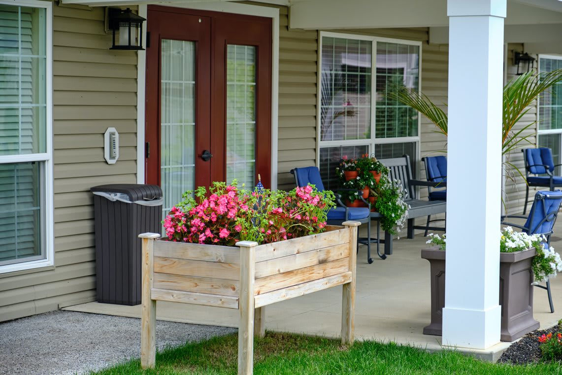 A cozy porch with a wooden planter box filled with vibrant flowers and comfortable patio furniture.