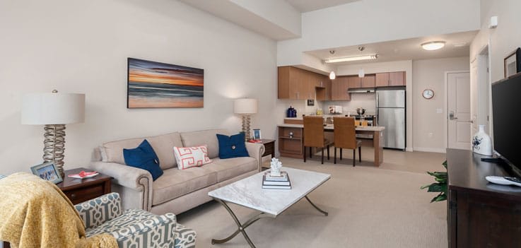 A modern open-plan living room with a stylish kitchen and dining area, featuring contemporary furniture and artwork.