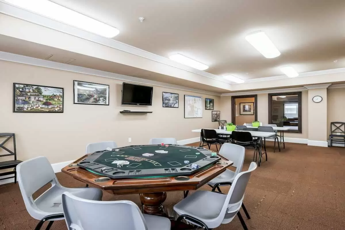 A spacious game room featuring a poker table surrounded by chairs, with decor and a television mounted on the wall.