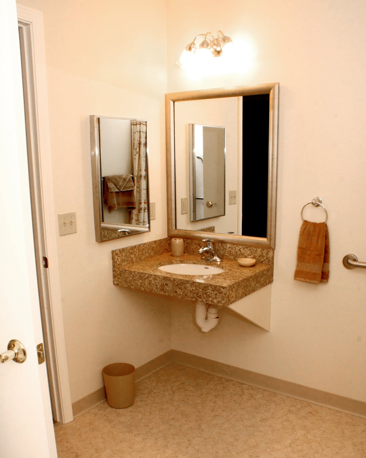 A bathroom interior featuring a sink, mirror, and towel holder.