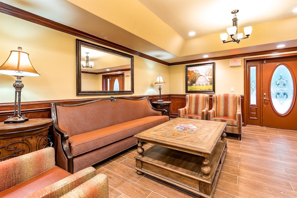 A cozy living room with a sofa, armchairs, and a wooden coffee table under warm lighting.