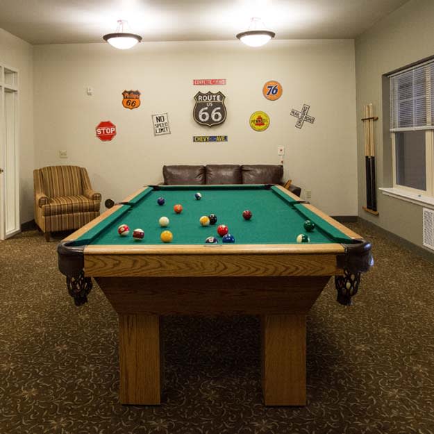 A cozy game room featuring a pool table and comfortable seating, adorned with retro wall art.