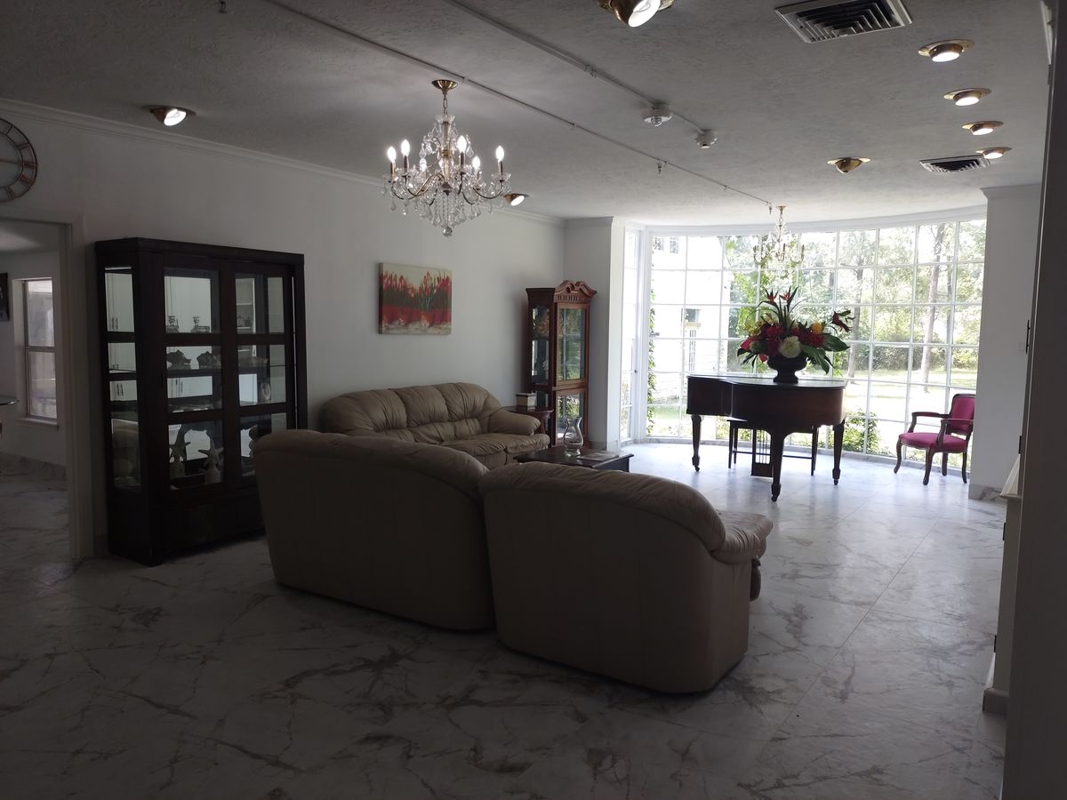 A well-lit living room featuring a comfortable sofa, a grand piano, and elegant decor.