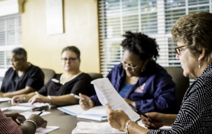 A group of people engaged in a meeting, reviewing documents in an office setting.