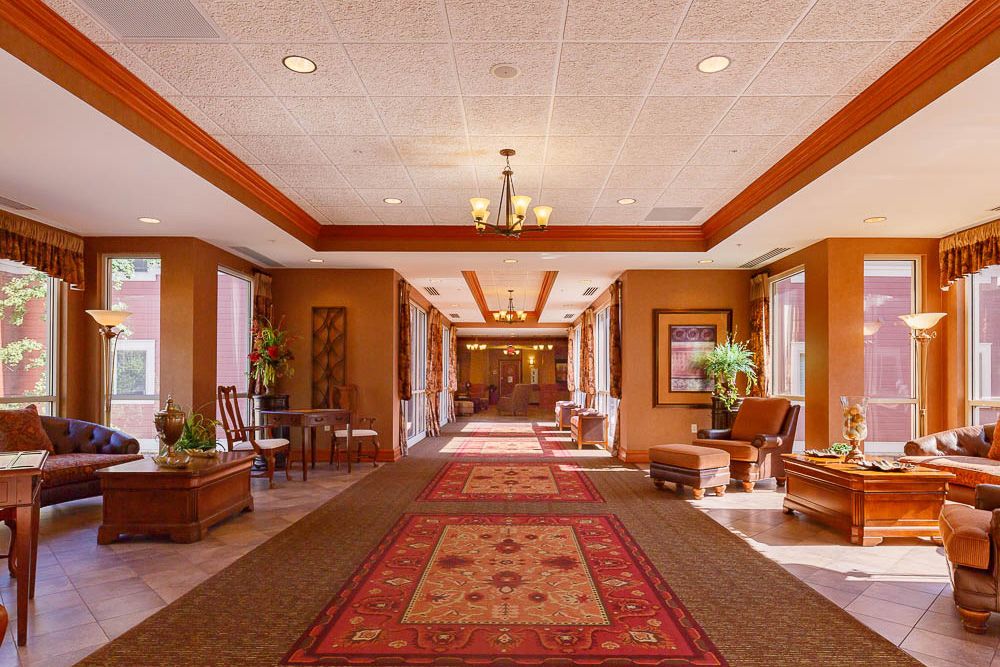 A spacious hallway with a red carpet, elegant seating areas, and decorative lighting.