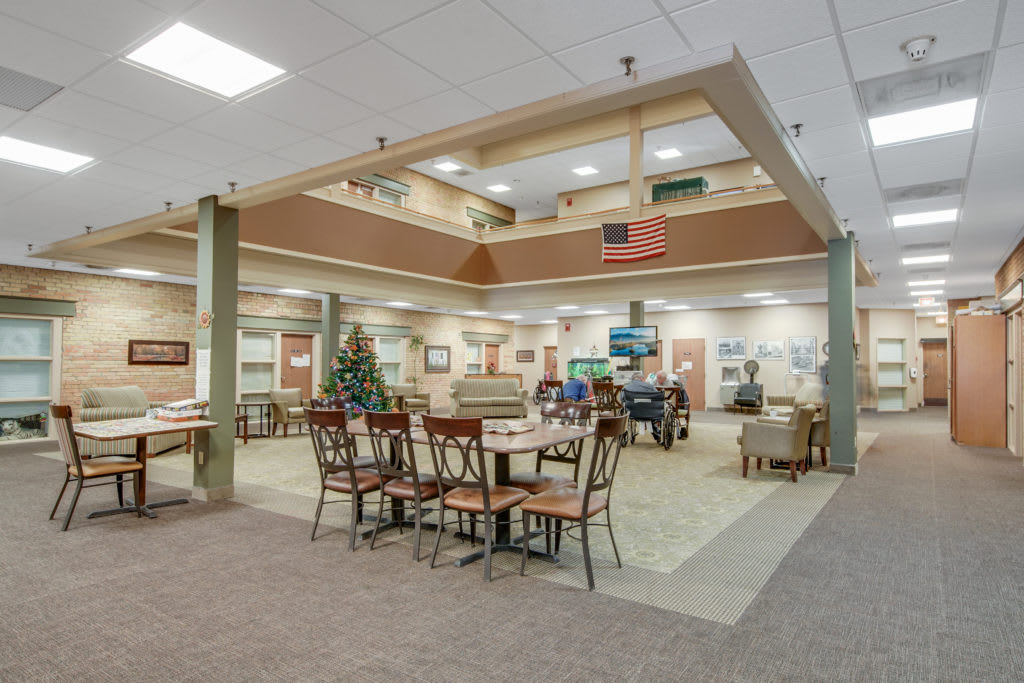 A spacious lobby area with tables and chairs, decorated with warm lighting and decor.