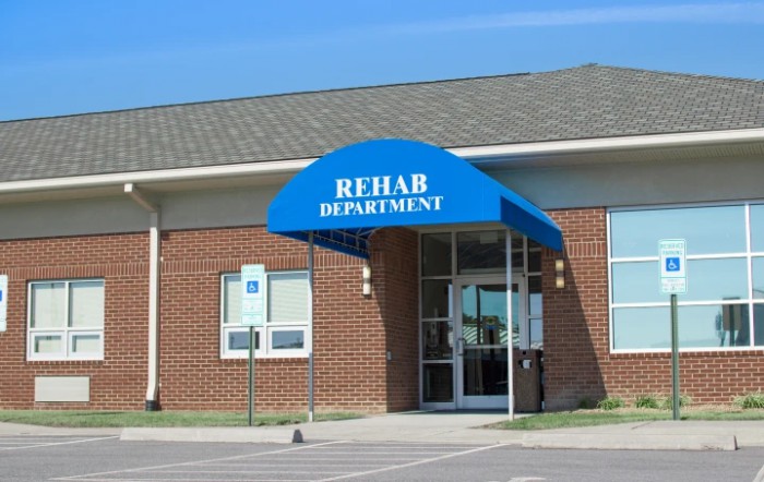 Entrance to a rehabilitation department with a blue awning.