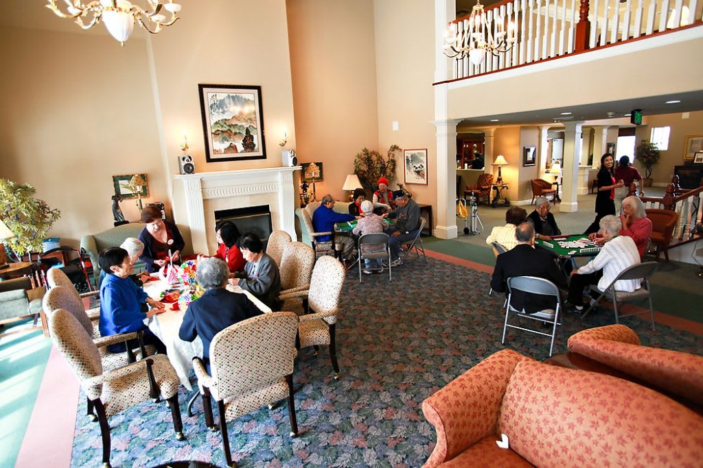 A group of people socializing in a spacious living room with comfortable seating and decor.