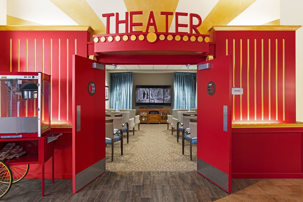 A vibrant red theater entrance leading to a cozy seating area with a large screen.
