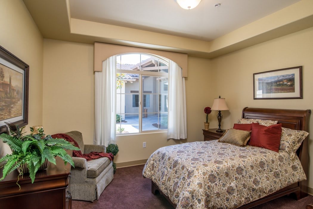 A cozy bedroom with a large window, bed, and comfortable seating.