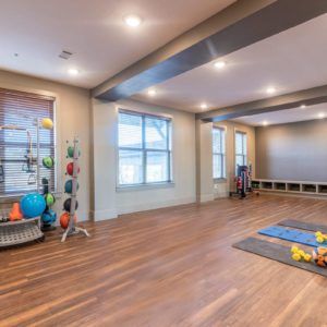 A spacious yoga studio with hardwood floors and various gym equipment.
