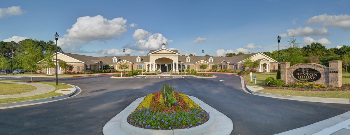 A well-manicured building entrance with vibrant landscaping and a clear sky.