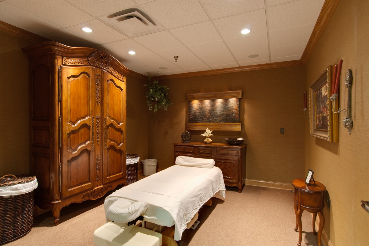 A cozy massage room with warm lighting and classic wooden furniture.