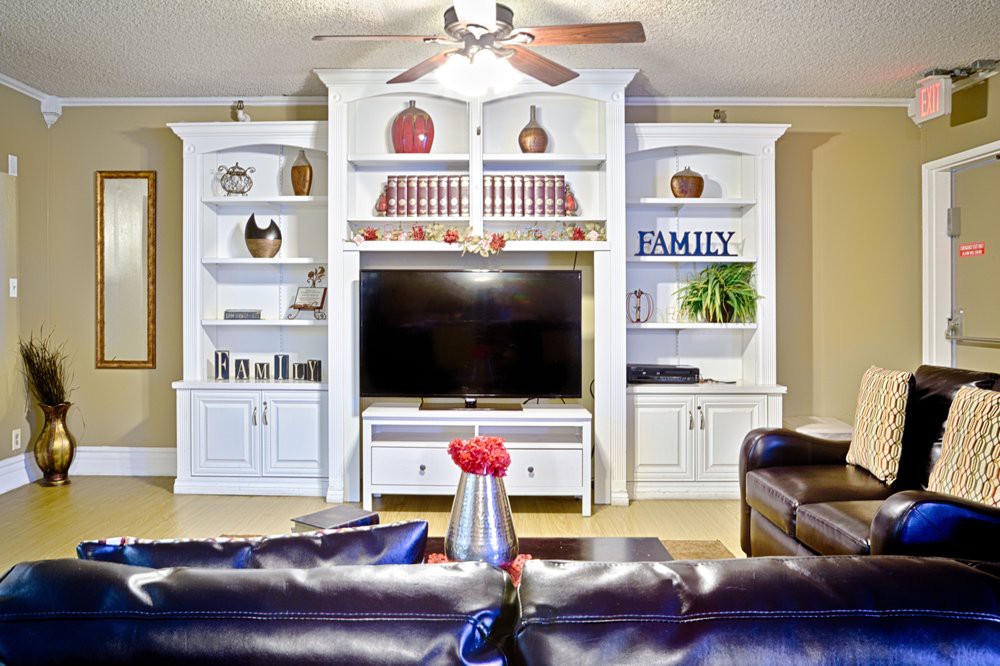 A cozy living room with a large entertainment center featuring a television, bookshelves, and decorative items.