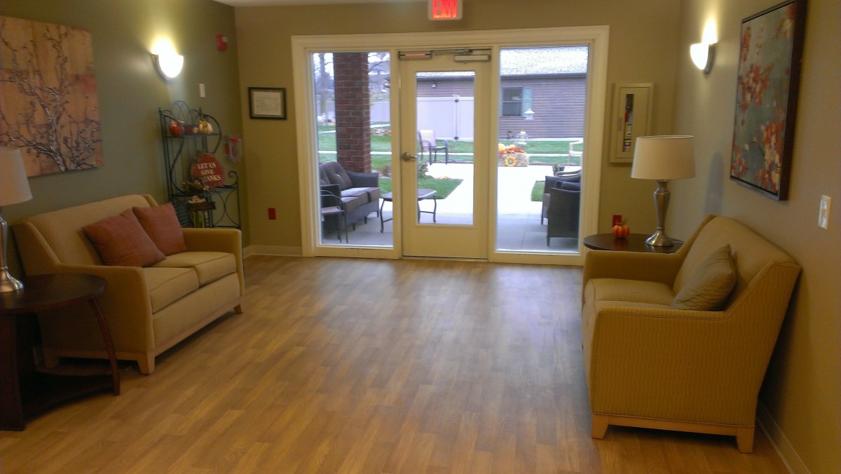 A cozy lounge area with sofas and a large windowed door leading outside.