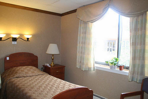 A cozy hotel room featuring a single bed and natural light from a window.