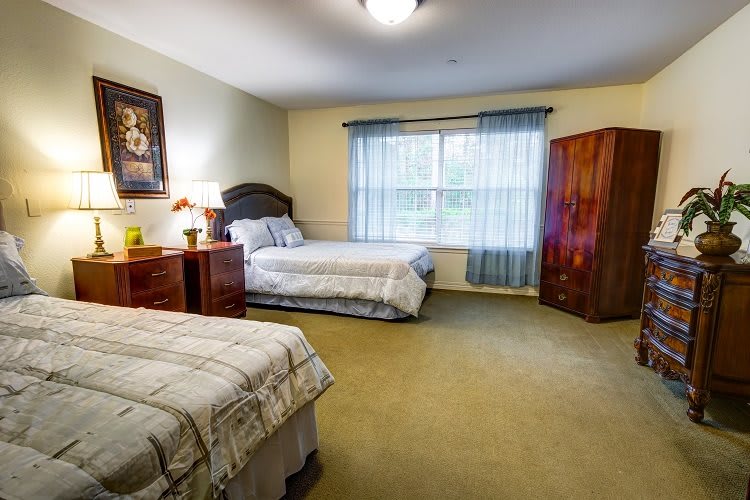 A spacious bedroom with two beds, wooden furniture, and a large window with curtains.