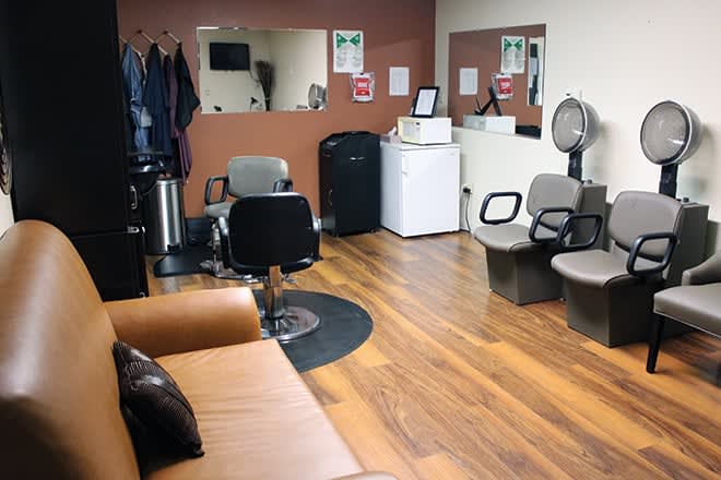 A cozy hair salon interior with styling chairs, mirrors, and a small lounge area.
