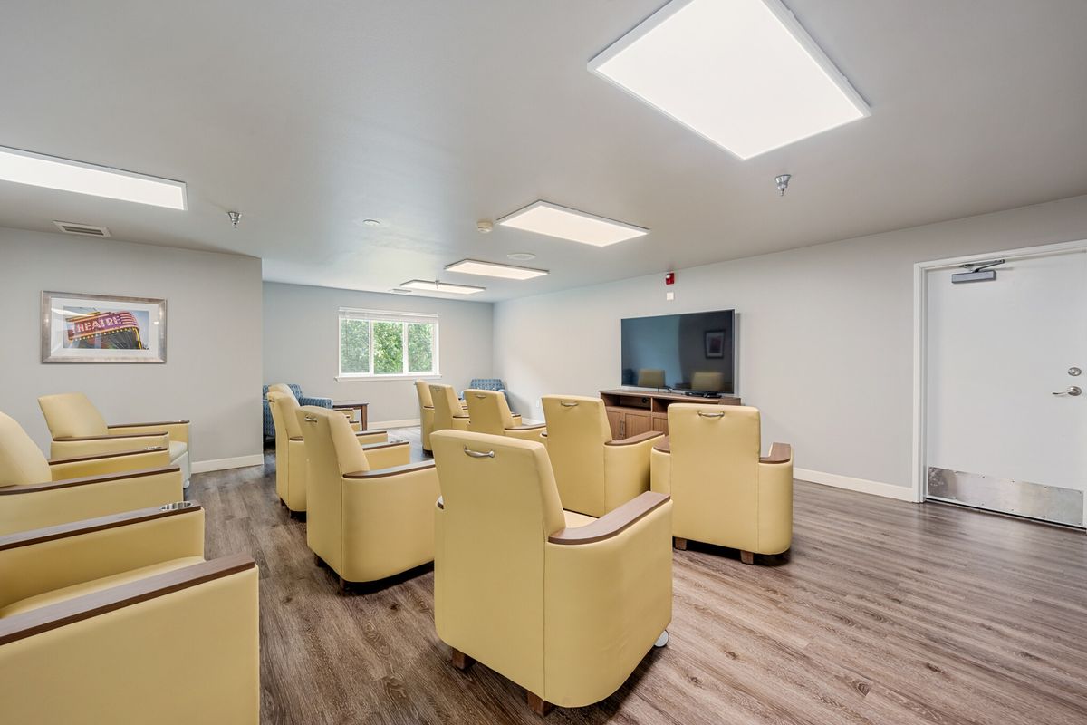 A modern home theater room with comfortable yellow armchairs and a large screen TV.