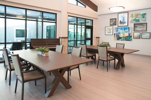 A modern dining area featuring elegant wooden tables and chairs, enhanced by ample natural light from large windows.
