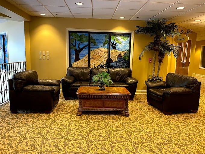 A cozy lobby area with leather seating, a wooden table, and decorative plants.