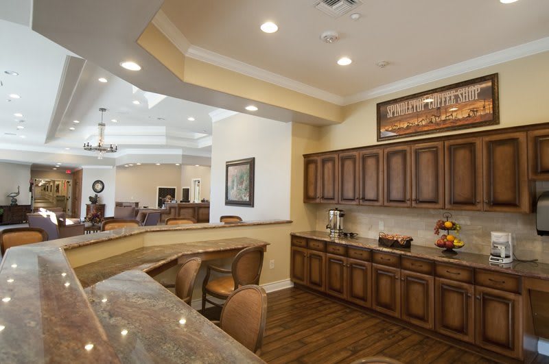 A modern kitchen and dining area with wooden cabinets and elegant lighting.