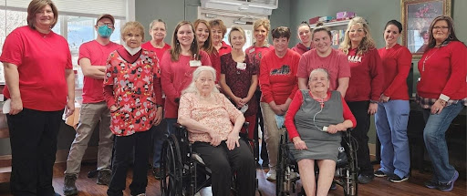 A cheerful gathering of healthcare workers and residents, united in their red attire to promote community spirit and support.