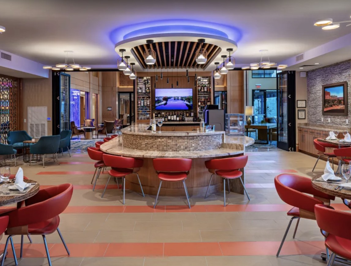 A modern bar with a central counter and red seating.
