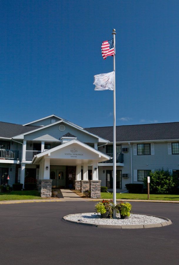 A two-story building with an entrance canopy, featuring American and white flags in front.