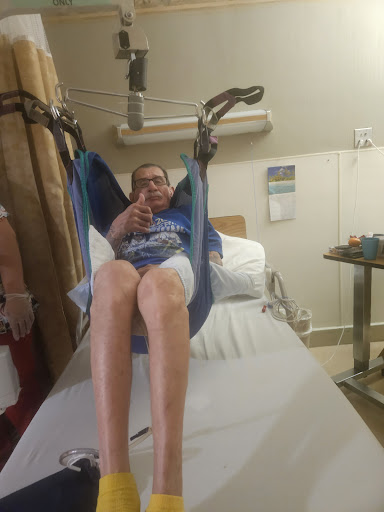 A patient using a lift to get from the bed, showcasing the use of medical equipment in a hospital setting.
