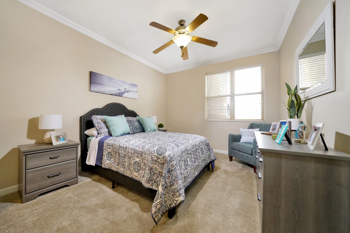 A cozy bedroom with a double bed, bedside tables, and a ceiling fan.