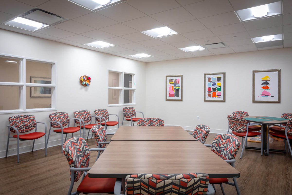 A brightly lit conference room featuring colorful chairs and artwork on the walls.
