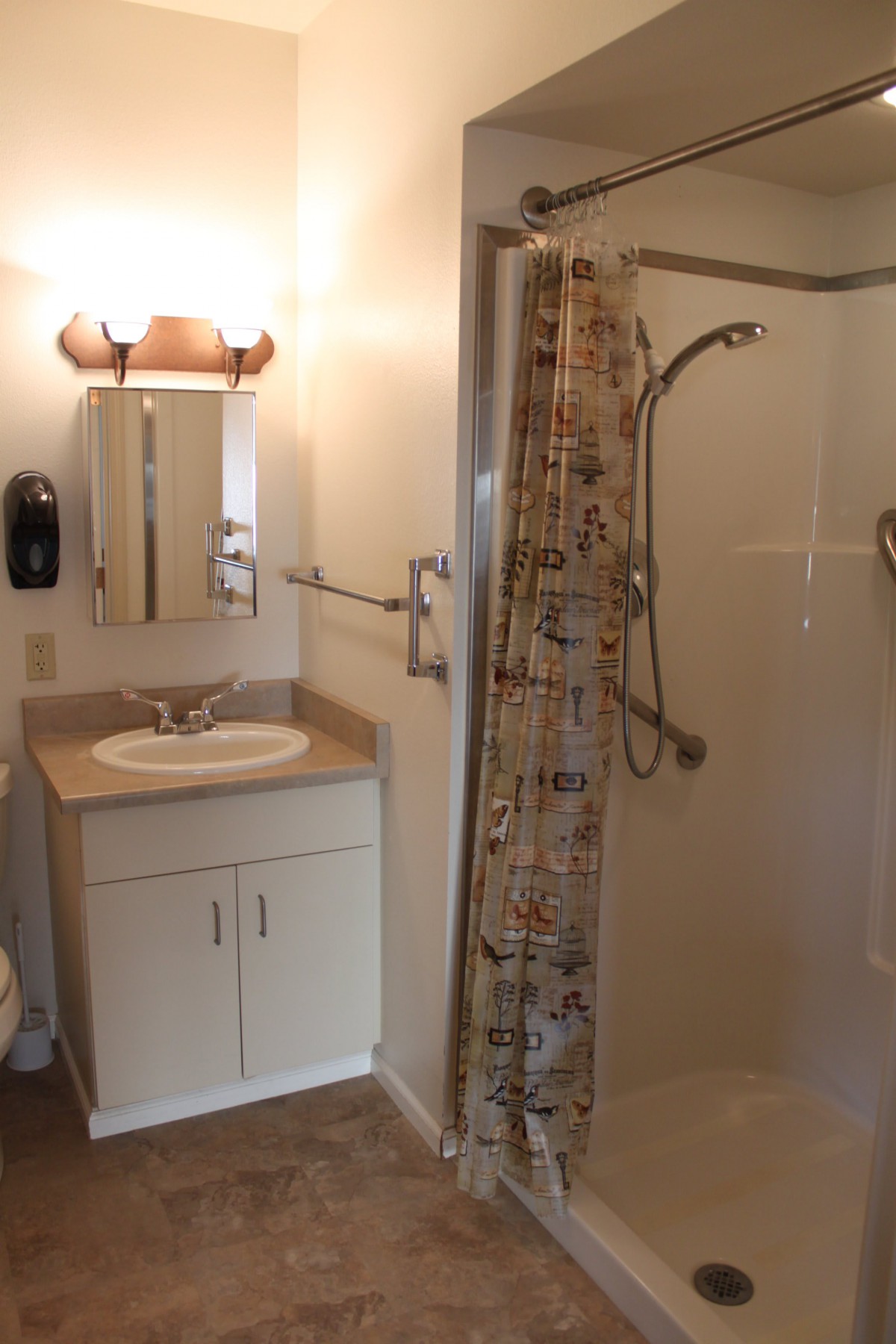 A modern bathroom featuring a sink with a mirror, shower with a curtain, and ambient lighting.